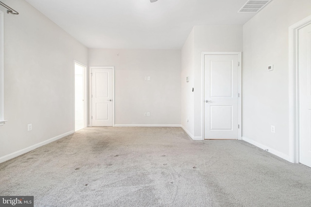 carpeted spare room with visible vents and baseboards