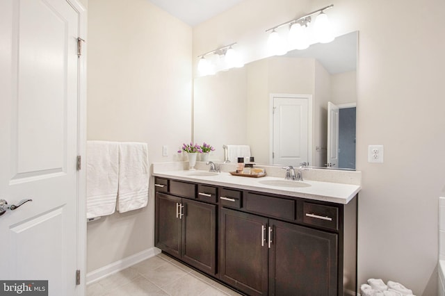 bathroom with double vanity, tile patterned flooring, a sink, and baseboards