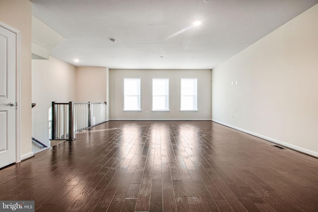 empty room featuring wood finished floors, visible vents, and baseboards