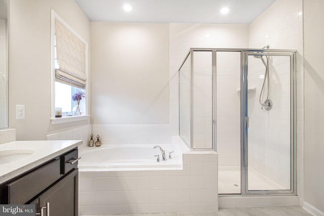 bathroom with a stall shower, a garden tub, and vanity