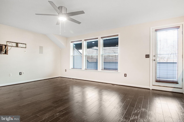 spare room featuring dark wood-style flooring, a ceiling fan, and baseboards