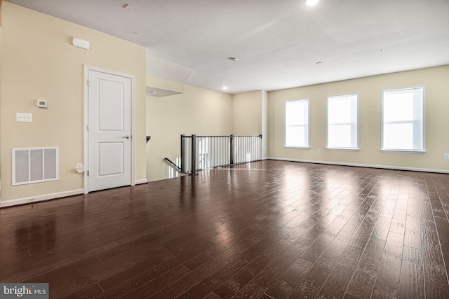 spare room featuring baseboards, visible vents, and wood finished floors