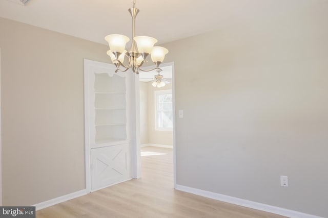 unfurnished dining area with an inviting chandelier, light wood-style flooring, and baseboards