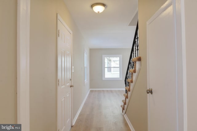 hallway featuring stairs, baseboards, and light wood-style floors