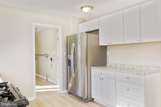 kitchen featuring stainless steel fridge with ice dispenser, light wood-style floors, white cabinets, light stone countertops, and baseboards