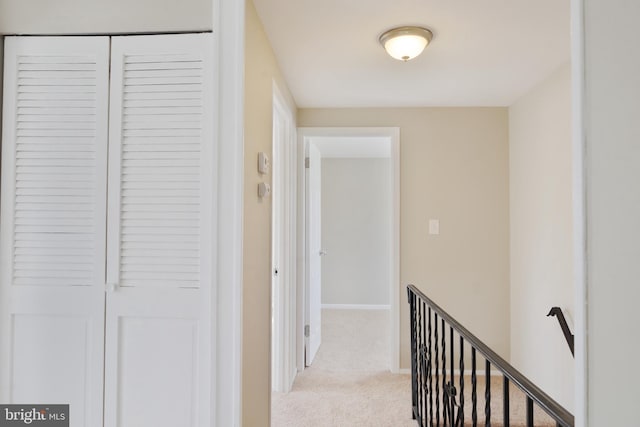 corridor with baseboards and light colored carpet