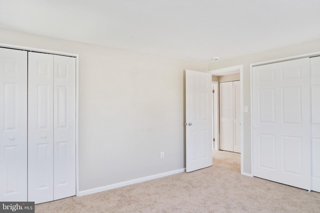 unfurnished bedroom featuring light carpet and baseboards