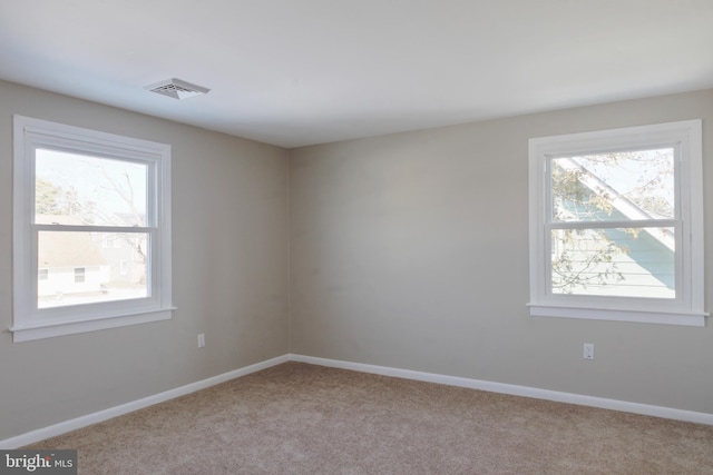 spare room with light carpet, visible vents, and baseboards