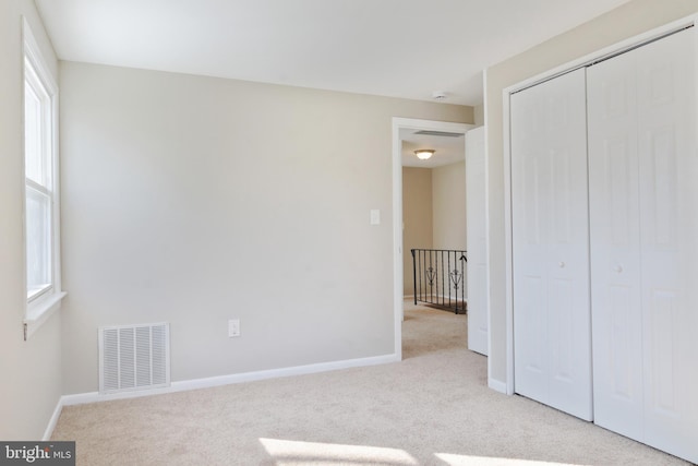 unfurnished bedroom with light carpet, baseboards, and visible vents