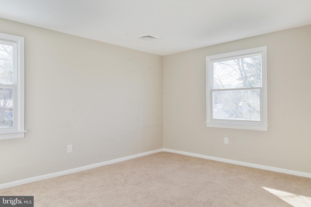 unfurnished room with a wealth of natural light, light colored carpet, and baseboards