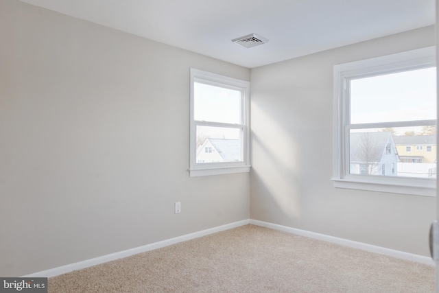 unfurnished room with light carpet, visible vents, and baseboards