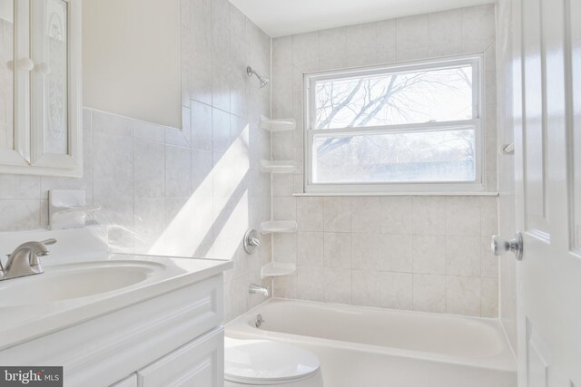 bathroom with toilet, vanity, washtub / shower combination, and tile walls