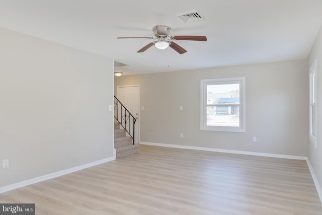 empty room featuring visible vents, stairway, baseboards, and light wood finished floors