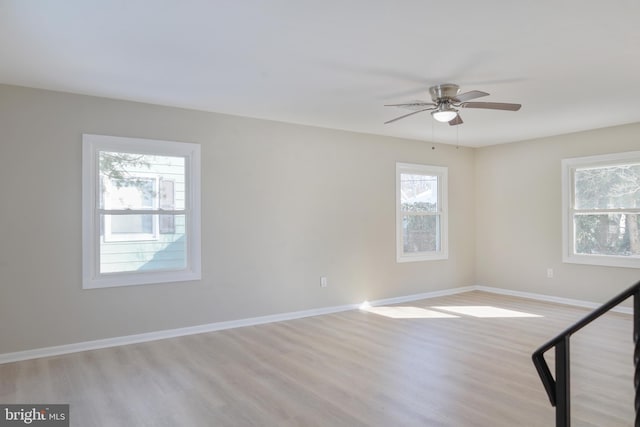 spare room with light wood-style floors, a ceiling fan, and baseboards