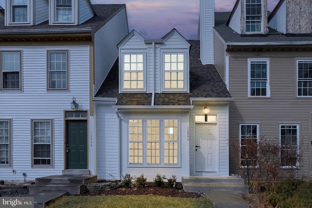 townhome / multi-family property with a shingled roof and a chimney