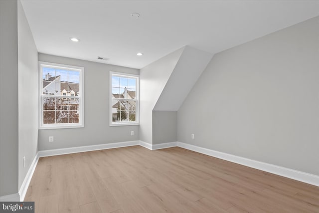 additional living space with light wood-type flooring, visible vents, baseboards, and recessed lighting