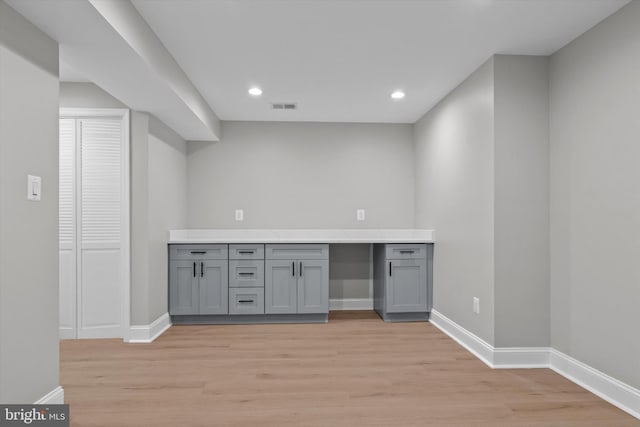 bar with light wood-style flooring, visible vents, and baseboards