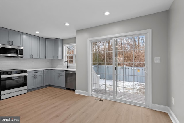 kitchen with visible vents, light wood-style floors, light countertops, appliances with stainless steel finishes, and backsplash