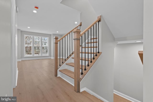 stairway with baseboards, wood finished floors, and recessed lighting