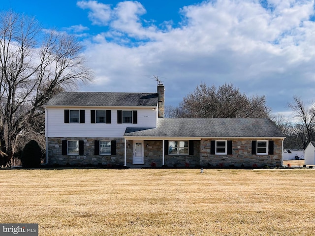 view of front of home with stone siding, a chimney, and a front lawn