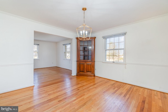 spare room featuring wood-type flooring, an inviting chandelier, and ornamental molding