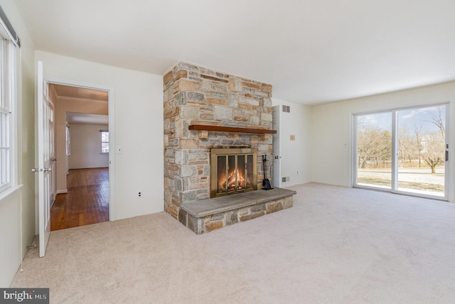 unfurnished living room with carpet floors, plenty of natural light, and a fireplace