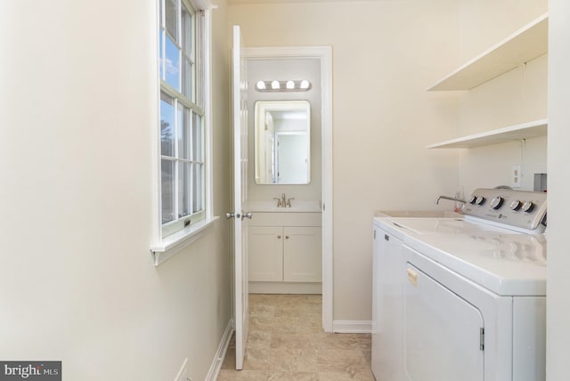 laundry room featuring a sink, baseboards, washing machine and dryer, and laundry area