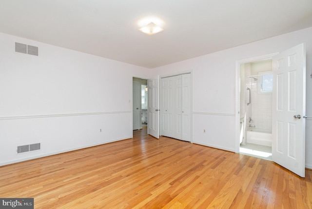 unfurnished bedroom with baseboards, visible vents, ensuite bath, and light wood-style floors