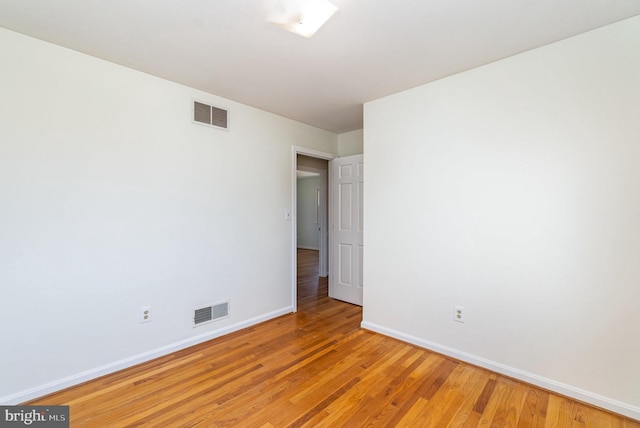 spare room with light wood-style floors, visible vents, and baseboards