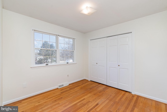 unfurnished bedroom featuring a closet, visible vents, light wood-type flooring, and baseboards