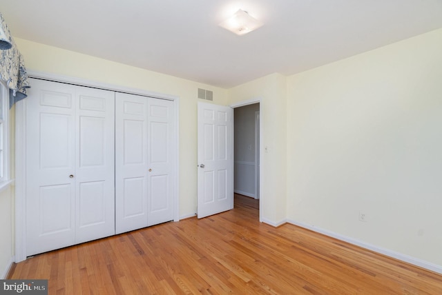 unfurnished bedroom featuring light wood-style flooring, baseboards, visible vents, and a closet