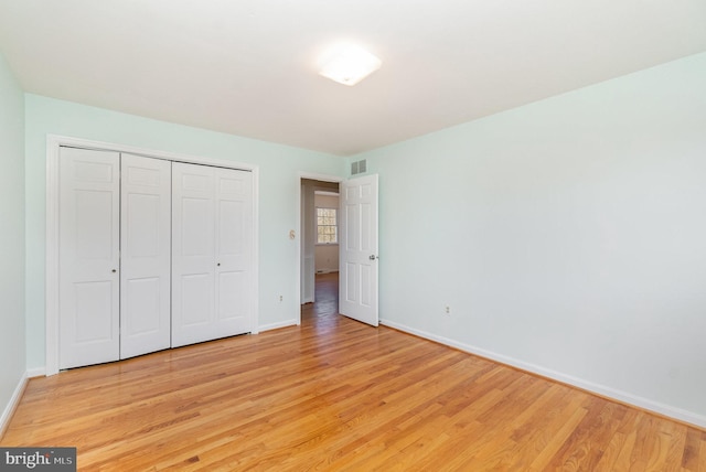 unfurnished bedroom with baseboards, visible vents, a closet, and light wood-type flooring