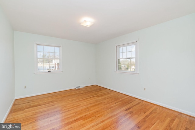 unfurnished room with baseboards, visible vents, and light wood finished floors