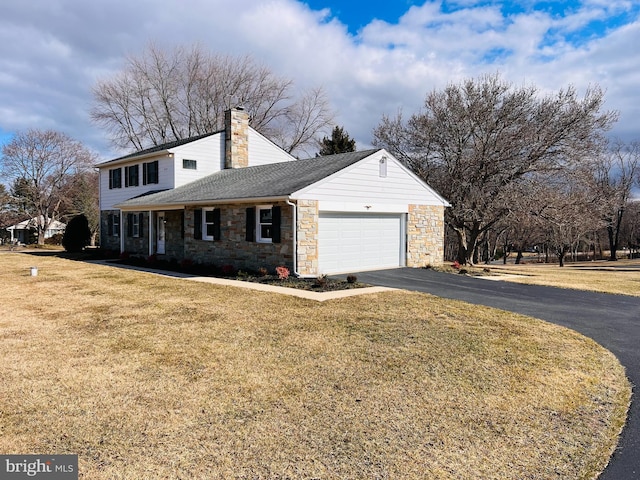 view of front of home featuring aphalt driveway, a garage, a chimney, and a front lawn