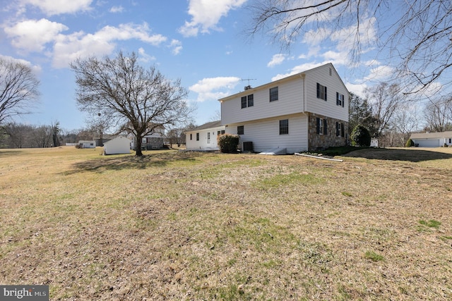 back of house with central air condition unit and a lawn