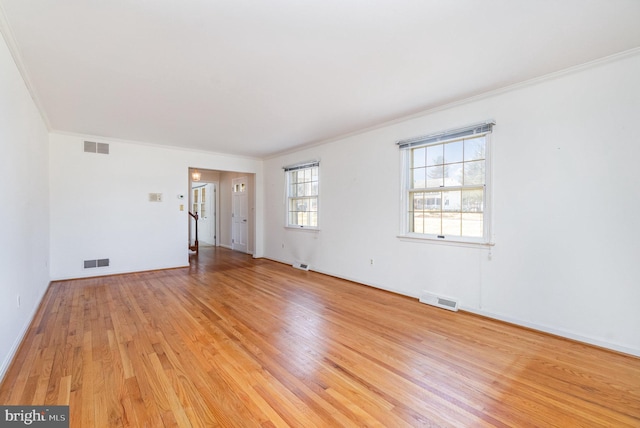 empty room featuring visible vents, light wood-style floors, and ornamental molding