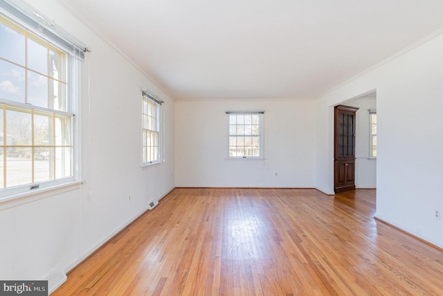 empty room with visible vents, crown molding, and light wood finished floors