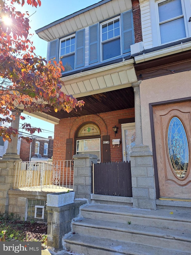 view of exterior entry with covered porch and brick siding