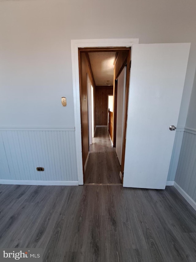 hall with dark wood-style flooring and wainscoting