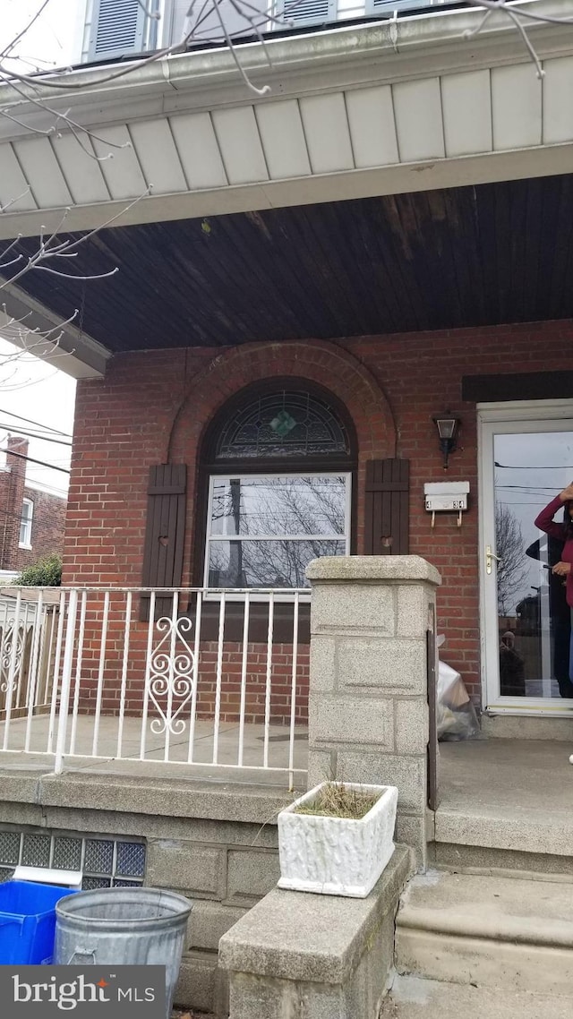 property entrance with covered porch and brick siding