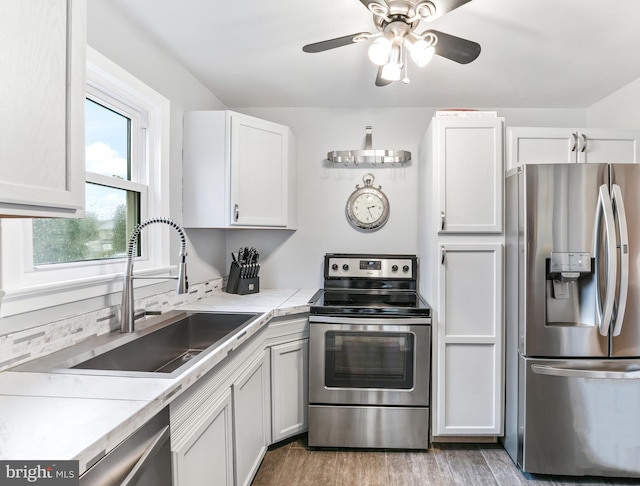 kitchen featuring light countertops, appliances with stainless steel finishes, light wood-style floors, white cabinets, and a sink