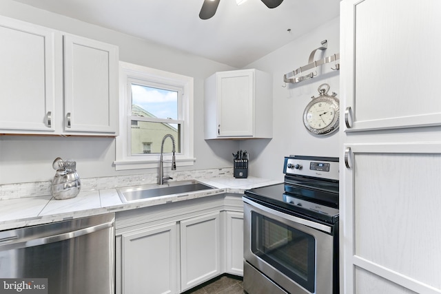 kitchen featuring stainless steel appliances, a ceiling fan, white cabinetry, a sink, and light stone countertops