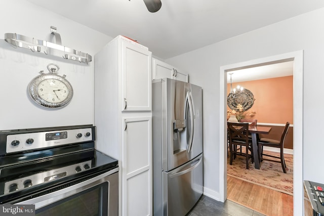 kitchen with baseboards, white cabinets, appliances with stainless steel finishes, wood finished floors, and a chandelier