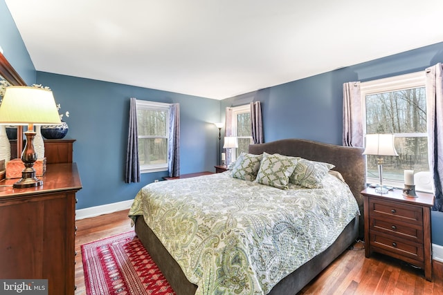 bedroom featuring multiple windows, baseboards, and wood finished floors