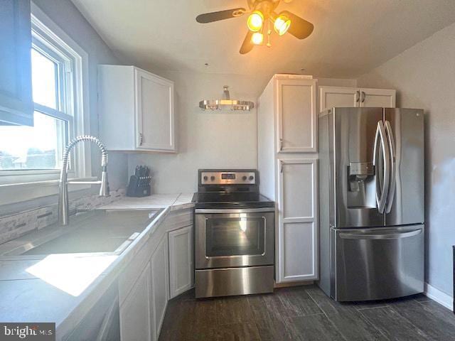 kitchen with dark wood-style floors, light countertops, appliances with stainless steel finishes, white cabinetry, and a sink