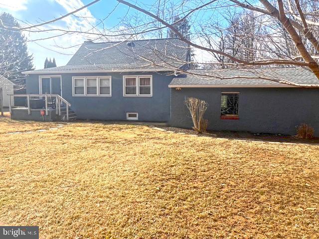 rear view of house with a lawn and stucco siding