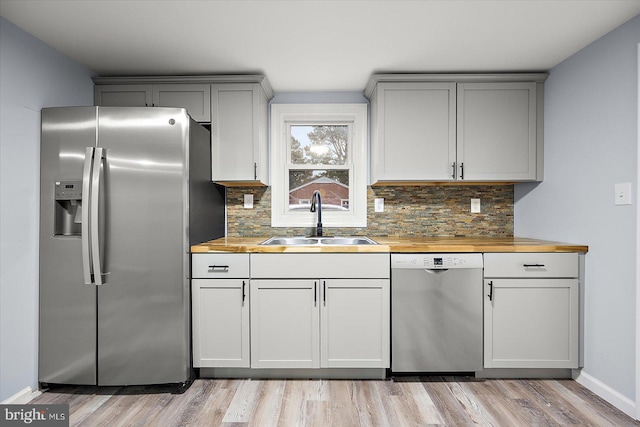 kitchen with appliances with stainless steel finishes, gray cabinets, a sink, and decorative backsplash