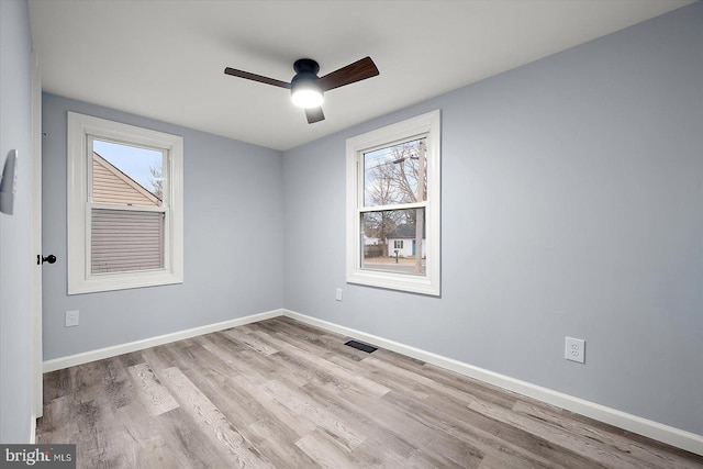 unfurnished room featuring plenty of natural light, wood finished floors, a ceiling fan, and baseboards