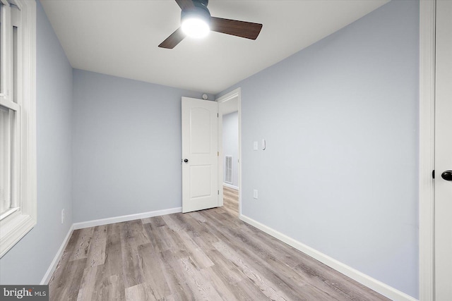 unfurnished bedroom featuring a ceiling fan, visible vents, baseboards, and wood finished floors