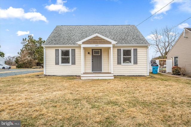 bungalow-style home featuring roof with shingles and a front lawn